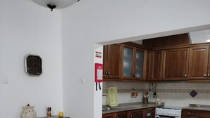 Une cuisine avec des meubles en bois, un poêle blanc et un coin repas comprenant une table et des chaises.