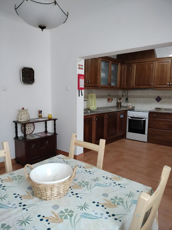 Una cocina con armarios de madera, una estufa blanca y un comedor con mesa y sillas.