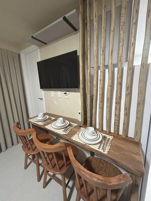 A dining area with a long wooden table set for four, equipped with plates, cups, and cutlery.