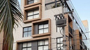 A modern multi-story building with a mix of brick and glass facades, large windows, and a gated entrance. - Flat Cabo Branco Aurea 50m do mar 105 (Joao Pessoa)