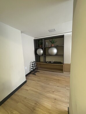 A room with a wooden floor, a built-in shelf unit with decorative items, and a small rack with multiple hooks. - Flat Cabo Branco Aurea 50m do mar 105 (Joao Pessoa)
