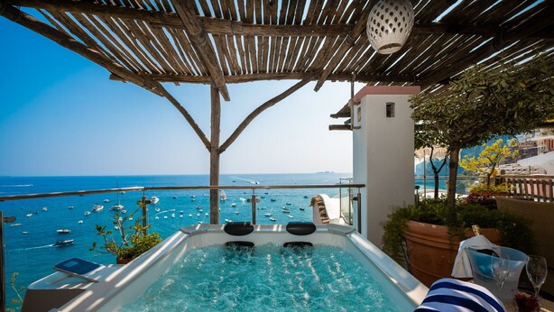 A hot tub with a view of the sea and boats, a pergola overhead, and a white building in the background. - Room-breathtaking Suite With Sea View in (Positano)