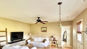 A living room with a sofa, a TV, a ceiling fan, and a dining area with a table and chairs. - Stay at Jordan Valley Vineyards Barnhouse (Jordan Station)