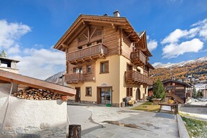 Ein mehrstöckiges Holzgebäude mit Balkonen, einer Stein-Fassade und einer Bergkulisse.