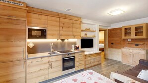 Una cocina moderna con armarios de madera, microondas, horno y pileta.