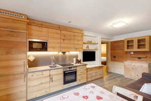 A modern kitchen with wooden cabinets, a microwave, an oven, and a sink. - Apartment 'Gembro' with Mountain View, Shared Garden and Wi-Fi (Livigno)