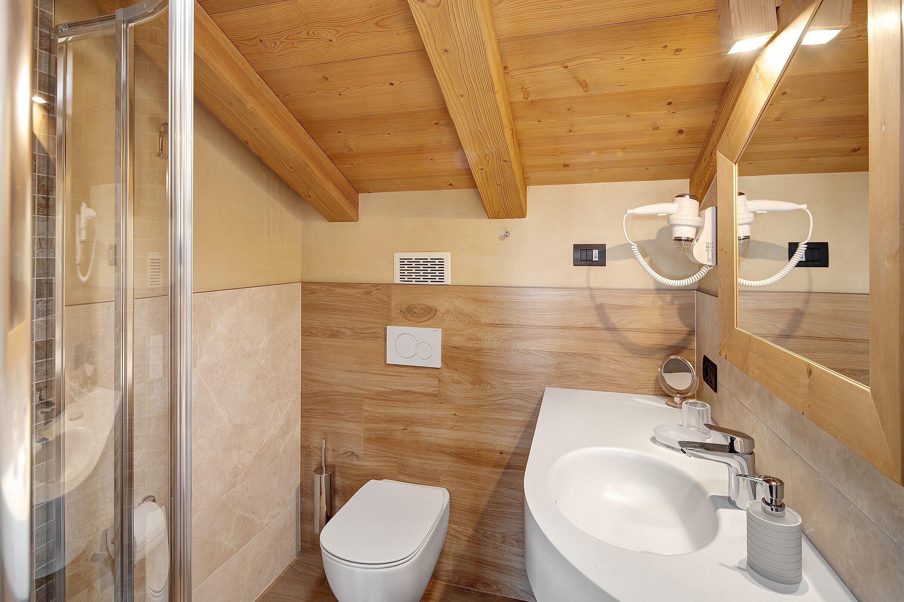 Een moderne badkamer met douche, toilet, wastafel en spiegel.