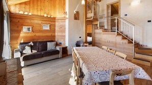A wooden interior with a sofa, dining table, and staircase.