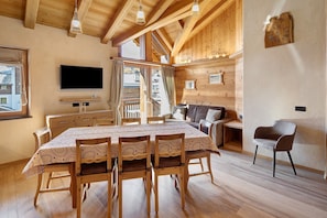 A wooden interior with a dining table, chairs, a TV, and a sofa. - Apartment 'Larice' with Mountain View, Shared Garden and Wi-Fi (Livigno)