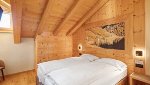 A wooden room with a bed, a chair, a painting, and a wall-mounted light. - Apartment 'Rovere' with Mountain View, Shared Garden and Wi-Fi (Livigno)