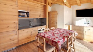 A wooden kitchen with a dining table, wooden cabinets, and a built-in oven. - Apartment 'Rovere' with Mountain View, Shared Garden and Wi-Fi (Livigno)