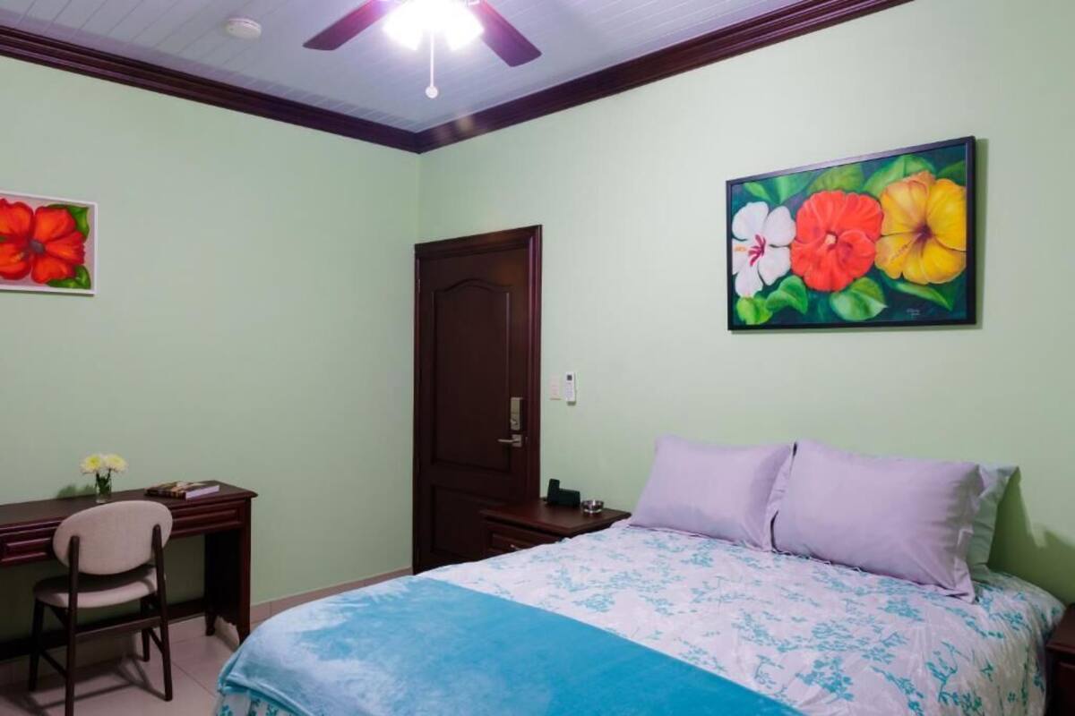 A bedroom with a bed, desk, chair, and a door.