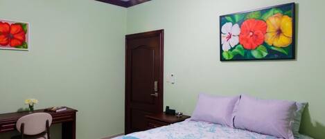A bedroom with a bed, desk, chair, and a door.