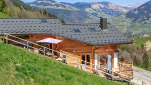 Una cabaña de madera con techo inclinado, un balcón y vistas a las montañas.