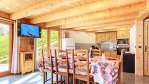 Un interior de madera con comedor, cocina y una pantalla de televisión.