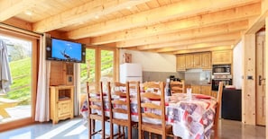 Un intérieur en bois comprenant un coin repas, une cuisine et un écran de télévision.