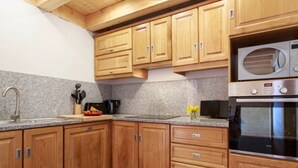Una cocina con armarios de madera, microondas, cafetera y estufa.