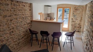 Ein Zimmer mit Steinwänden, einer Küchenzeile und vier Barhocker.