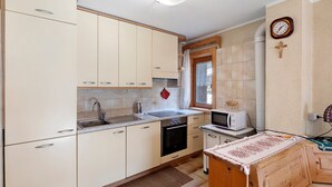 A compact kitchen with a sink, stove, microwave, and wooden cabinets. - Apartment 'Di Bernardin' with Mountain View and Wi-Fi (Livigno)