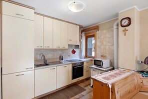 A compact kitchen with a sink, stove, microwave, and wooden cabinets.