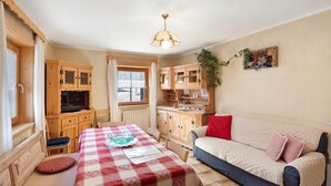 A cozy room with a dining table, a sofa, wooden cabinets, and a hanging plant. - Apartment 'Di Bernardin' with Mountain View and Wi-Fi (Livigno)