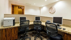 Une salle de conférence équipée de trois bureaux, chacun comprenant un écran d’ordinateur, un clavier et une souris. Une imprimante se trouve sur le côté gauche de la pièce.