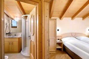 Interior de una cabaña de madera con baño, una cama y un escritorio pequeño.