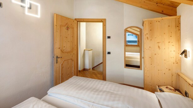 Un dormitorio con techo de madera, una cama, una mesita de noche y un espejo.
