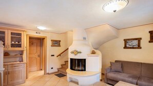 Una sala de estar con chimenea, un sofá, un armario de madera y una escalera.