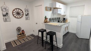 A modern kitchen with white cabinets, a central island, and two black stools.