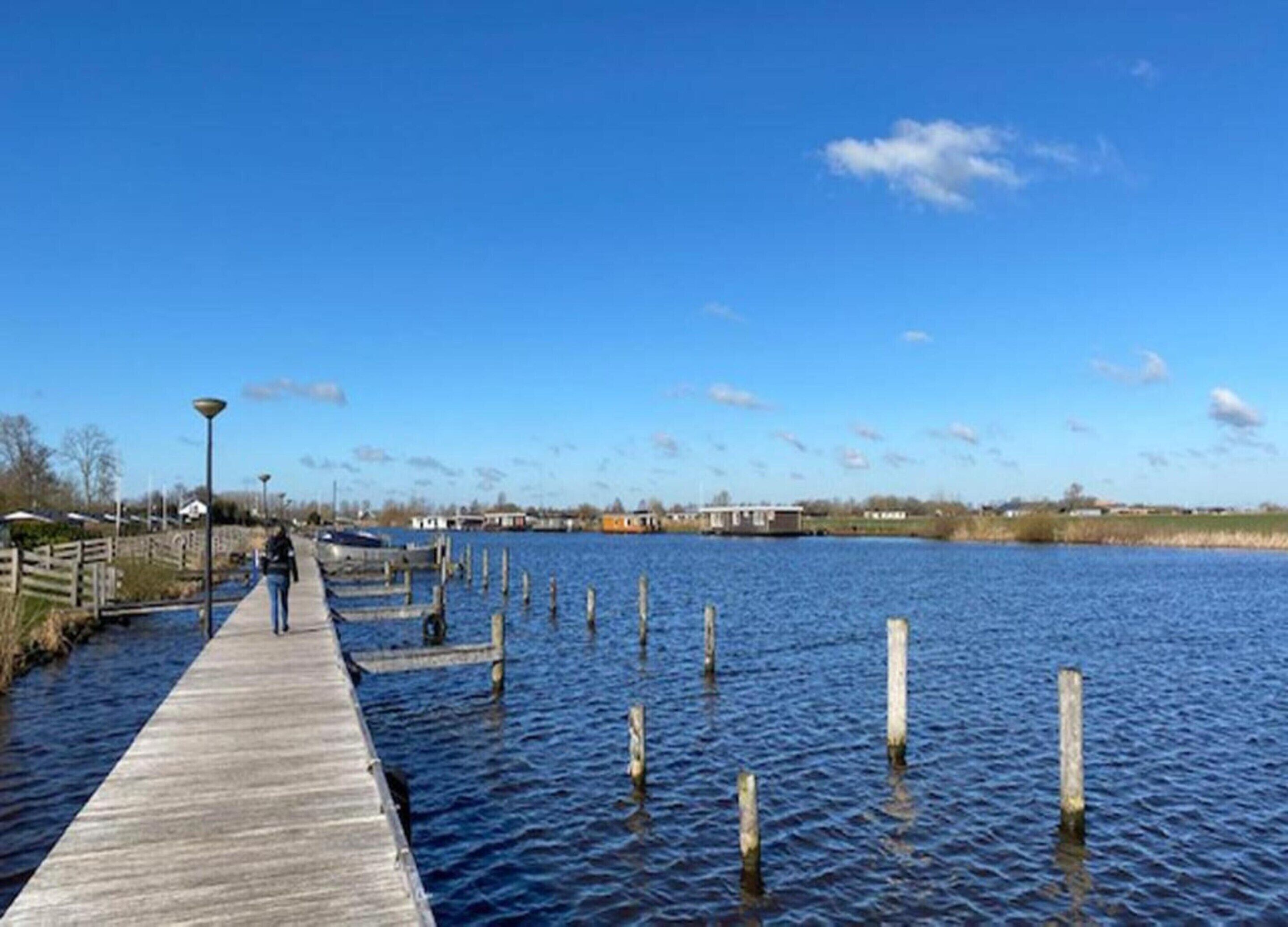 A wooden pier extending into a calm body of water with a clear sky above.