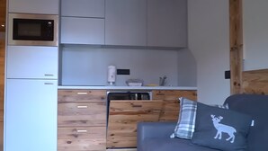 A compact kitchen with a microwave, a small refrigerator, and wooden cabinetry. - Apartment 'La Mirage' with Mountain View, Balcony and Wi-Fi (Livigno)