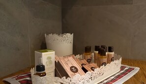 A wooden table with a white lace centerpiece, a box labeled 'ERVAMEA,' and several small bottles with labels. - Apartment 'La Mirage' with Mountain View, Balcony and Wi-Fi (Livigno)