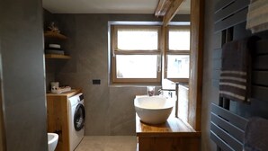 A compact bathroom with a washing machine, a sink, and a window. - Apartment 'La Mirage' with Mountain View, Balcony and Wi-Fi (Livigno)