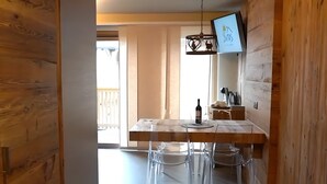 A wooden interior with a dining area featuring a table, chairs, and a hanging light fixture. - Apartment 'La Mirage' with Mountain View, Balcony and Wi-Fi (Livigno)