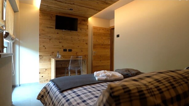 A room with a bed, a desk, and a TV mounted on the wall. - Apartment 'La Mirage' with Mountain View, Balcony and Wi-Fi (Livigno)