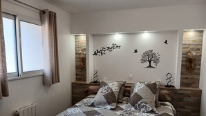 Un dormitorio con cama, cortinas, radiador, pared de piedra y decoración en la pared.