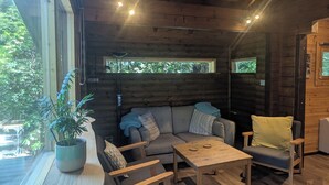 Een gezellig cabin-interieur met houten plafond, een bank, een eettafel en een plant in pot bij het raam.