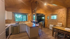 Een houten chalet van binnen, met een keuken, eethoek en een badkamer.