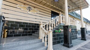 Ingresso di un edificio con una scalinata in marmo, uno stemma decorativo e una facciata piastrellata.