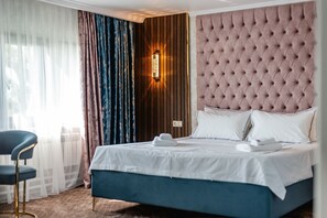 Ett hotellrum med en stor säng, en sänggavel i trä och en modern lampa.