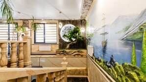 Un interno lussuoso con una scala in marmo, un grande affresco raffigurante un paesaggio fluviale e un soffitto decorato con un motivo lunare.