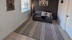 A living room with a grey sofa, two bear-themed wall art pieces, a patterned rug, and a door to the right. - Bear cave! (Tucson)