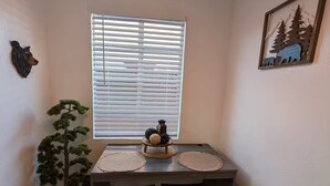 A corner room with a window, a small table with two stools, a potted plant, and a wall-mounted bear head decoration. - Bear cave! (Tucson)