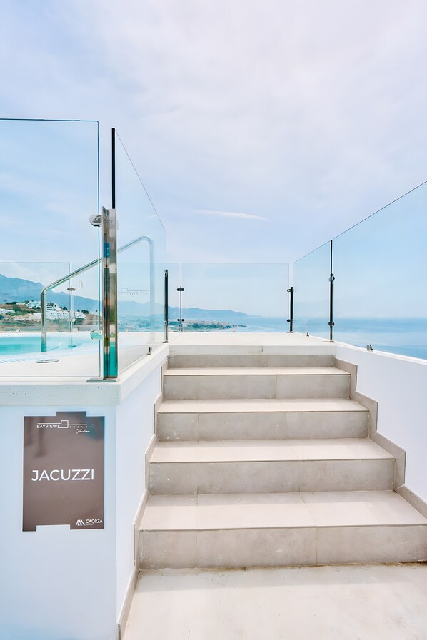 A staircase leading to a pool with a clear view of the sea and distant mountains.