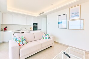 A modern living room with a sofa, a coffee table, and a kitchen in the background.