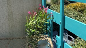 A balcony with a view of the sea, a potted plant with pink flowers, and a glass table with a mug. - Waterfront apartment (sea view) (Concarneau)