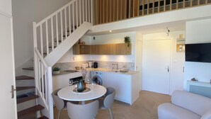 A modern apartment with a staircase leading to a loft bedroom, a dining area with a round table, and a living room with a sofa. - Waterfront apartment (sea view) (Concarneau)
