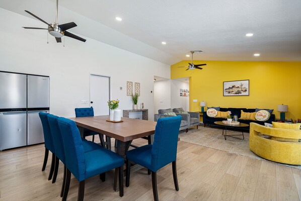 A modern living space with a dining area, kitchen, and seating area. - Hello Pool Spa Putt-Putt Billiards Games Firepit (Bermuda Dunes)
