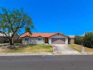 A single-story house with a red-tiled roof, a garage, and a driveway leading to the front door.